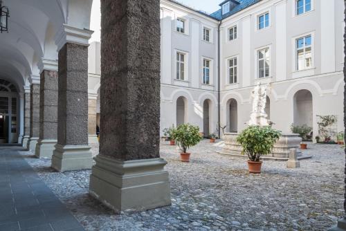 a building with a column and potted plants in a courtyard at Gästehaus im Priesterseminar Salzburg in Salzburg
