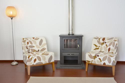 a living room with two chairs and a stove at Casa dos Botes - WhaleBoat House TER in São Caetano