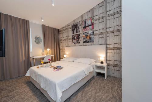 a bedroom with a white bed and a wooden wall at Downtown Boutique Hostel in Zadar