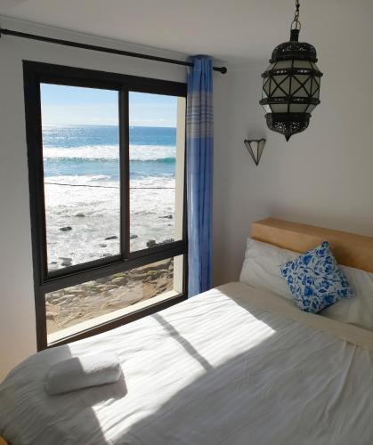 a bedroom with a window with a view of the ocean at Bouad Seafront Apartments & Rooms in Taghazout