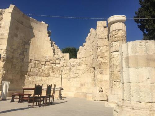 a table and chairs next to a stone wall at Zenzero e Limone in Siracusa