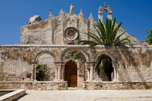 an old stone building with a palm tree in front of it at Zenzero e Limone in Siracusa