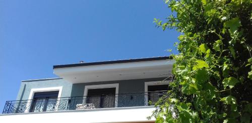 a white building with a balcony with a blue sky at Pela Veranda Exquisite Suites in Neos Marmaras
