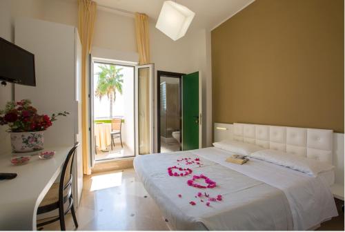 ein Schlafzimmer mit einem Bett mit rosa Blumen drauf in der Unterkunft Hyencos Hotel Calos in Torre San Giovanni Ugento