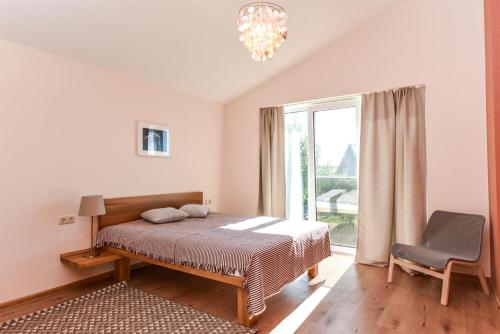una camera da letto con un letto, una sedia e una finestra di Atsipūskit a Palanga
