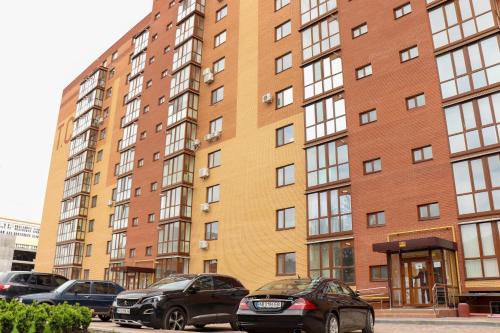 two cars parked in front of a tall building at Blue apartments on Kotsyubinsky Avenue in Vinnytsya