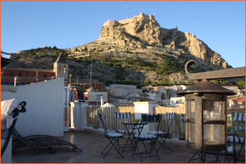 a balcony with chairs and a table and a mountain at Santa Barbara Guesthouse in Alicante