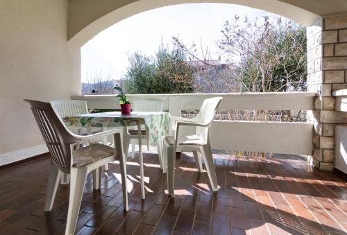 een tafel en stoelen op een balkon met een raam bij Apartments Luka in Pag