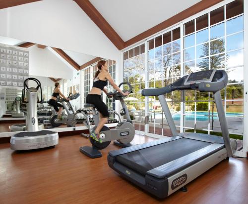 a woman exercising on a treadmill in a gym at Palheiro Village Resort in Funchal