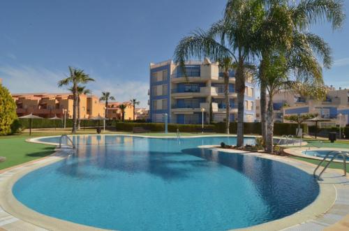 Cabo Roig - Blue Luxury Apartment في كابو رويج: مسبح كبير بالنخيل ومبنى