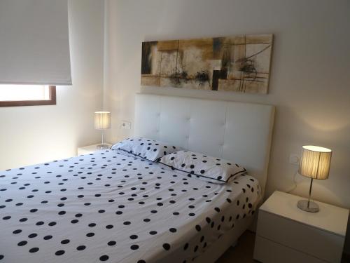 a bedroom with a white bed with two lamps at Las Azaleas in San Juan de los Terreros