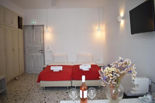 a bedroom with a bed with a red blanket and flowers at Andriani's Guest House in Mýkonos City