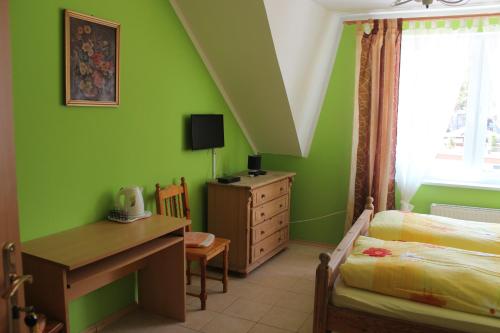 1 dormitorio con paredes verdes, escritorio y cama en Pension Dom Wypoczynkowy Ulla, en Pobierowo