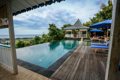 a swimming pool with two chairs and a house at The Kayu Manis Villa in Lovina