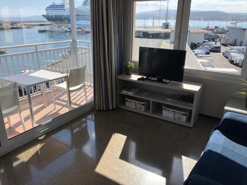 a living room with a flat screen tv and a balcony at Apartaments la Catifa in Palamós