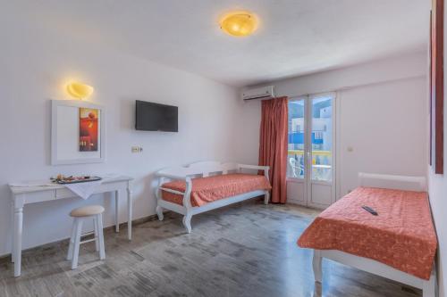 een slaapkamer met een bed, een bureau en een raam bij Irini Apartments in Chersonissos