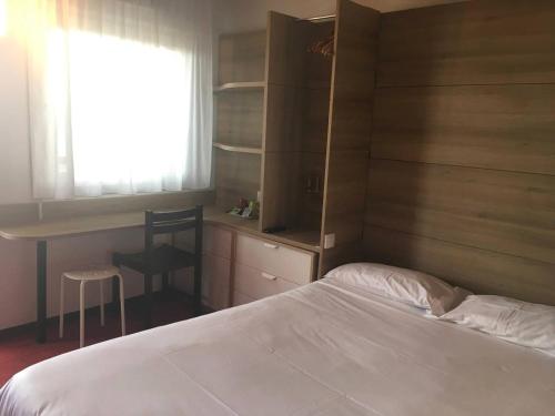 a bedroom with a bed and a desk and a window at So'Lodge Niort A83 in La Creche