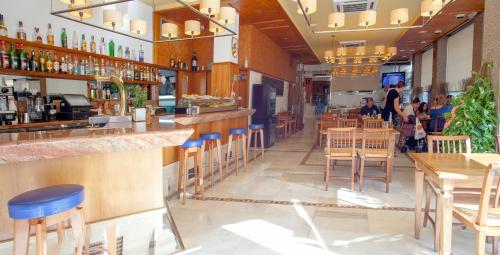 a restaurant with a bar with blue stools at Aparthotel Duquesa Playa in Santa Eularia des Riu