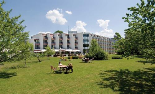 Ein Gebäude mit Leuten, die an einem Tisch im Park sitzen in der Unterkunft Parkhotel Brunauer in Salzburg