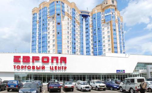 a parking lot with cars parked in front of a large building at Naugorka 76 in Oryol