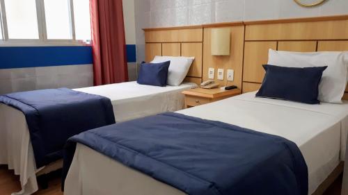 a hotel room with two beds with blue pillows at Hotel Único in Rio de Janeiro