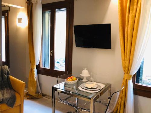 uma sala de estar com uma mesa de vidro e uma televisão em Suite Dream on the River em Veneza