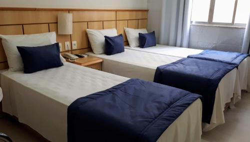 Habitación de hotel con 2 camas y almohadas azules en Hotel Único en Río de Janeiro