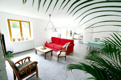 a living room with a red couch and a table at La Maison du Parc Affaires et Tourisme in Crépy-en-Valois
