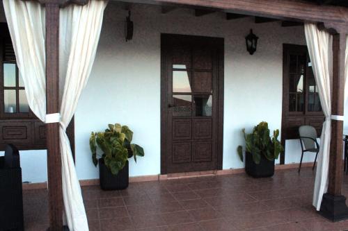eine Veranda eines Hauses mit zwei Topfpflanzen in der Unterkunft Mama Yé in Lodero