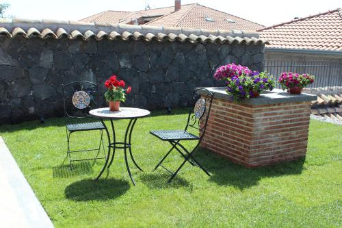 um jardim com uma mesa e duas cadeiras e flores em Martina Paradise Affitta Camere em Nicolosi