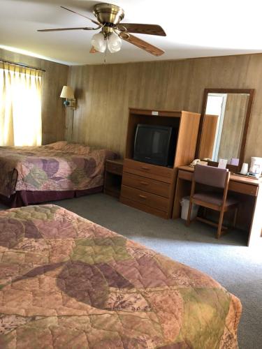 a hotel room with two beds and a flat screen tv at Coronado West Motel in Lindsborg