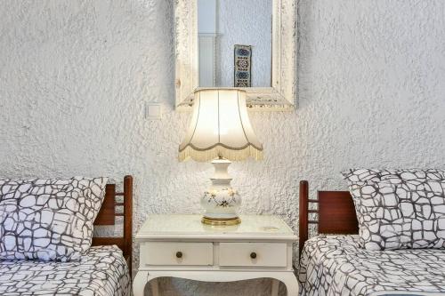 a table with a lamp on it next to two beds at Light-filled home with Garden near Beach in Anavissos