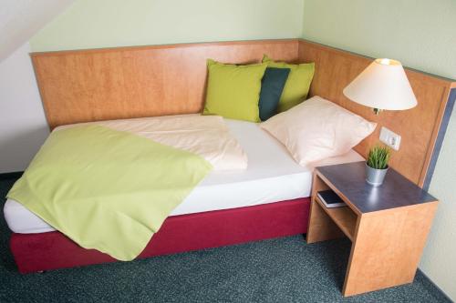 a bed with a wooden headboard and a table with a lamp at Hotel Stadt Gehrden in Gehrden