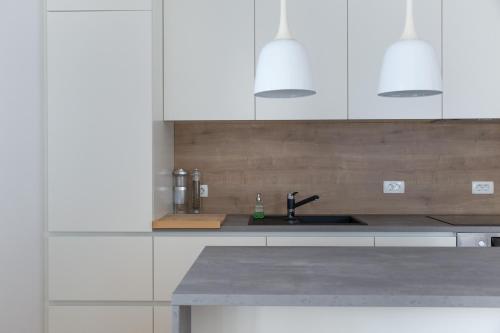 una cocina con armarios blancos y fregadero en Auredius Deluxe Sea Apartment, en Koper