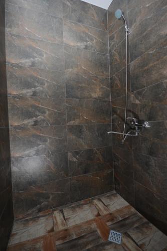 a bathroom with a shower with a stone wall at Olimpo Guest House in Akhaltsikhe