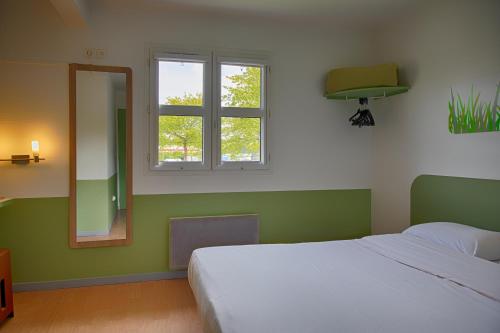 a bedroom with a bed and a mirror and a window at ibis budget Redon in Redon