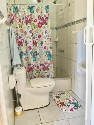 a bathroom with a toilet and a shower curtain at La Casa de Jessy in Máncora