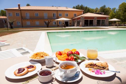 einen Tisch mit einem Tablett mit Frühstücksspeisen und einem Pool in der Unterkunft Agriturismo Creta Rossa in Torre di Ruggiero