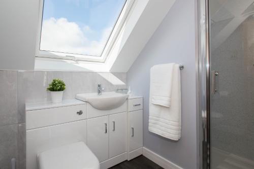 a white bathroom with a sink and a window at Fairfield B&B in Holsworthy