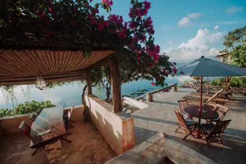 a patio with chairs and an umbrella and the water at Rock'n Reef in Uluwatu