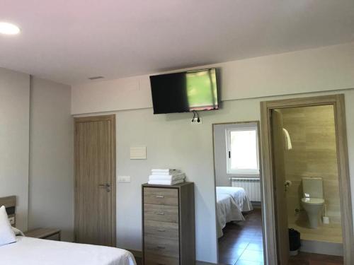 a hotel room with a television on the wall at Pensión CHE in O Pedrouzo
