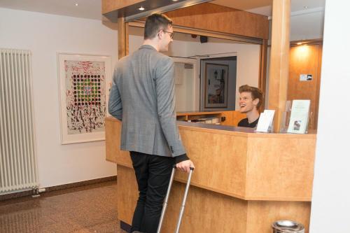 a man with a cane standing at a counter at Hotel Stadt Gehrden in Gehrden