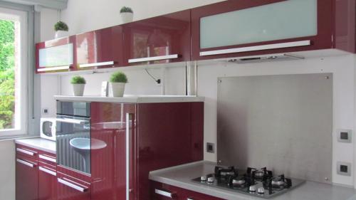 La cuisine est équipée de placards rouges et d'un four avec plaques de cuisson. dans l'établissement Gite Histoire de Maison, à Arras
