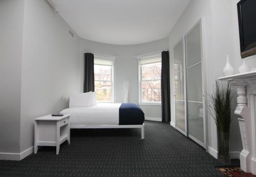 a white bedroom with a bed and a window at Stylish Newbury Street Studio, #4 in Boston