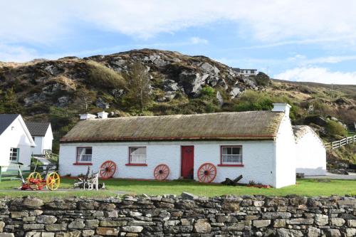 a white house with red doors and a stone wall at Slieve League House B&B in Teelin