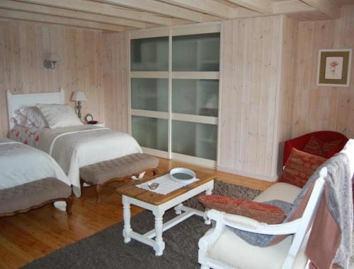 a bedroom with two beds and a chair and a table at La Charlisa in Pra-Loup