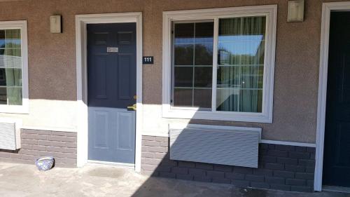 a house with blue doors and a bench in front at Pacific Motel in Gridley