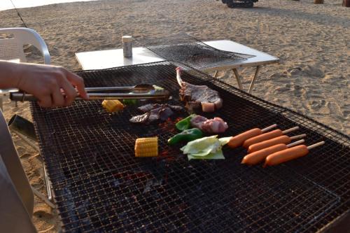 a person grilling meat and vegetables on a grill at Guest House Shiraishi in Kasaoka