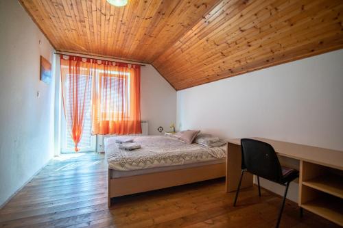 a bedroom with a bed and a desk and a window at House Marijana in Smoljanac