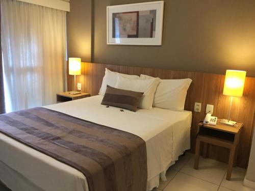 a bedroom with a large white bed with two lamps at RioStay Residence, Riocentro in Rio de Janeiro